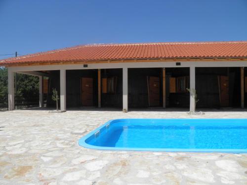 a blue swimming pool in front of a house at Agroturizam Duvančić - Konoba dida Marka in Drniš