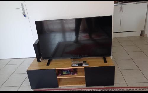 Elle comprend une télévision à écran plat installée au-dessus d'un support en bois. dans l'établissement Bel appartement Type F2 vaux en velin Village 69120, à Vaulx-en-Velin