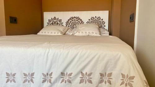 a bed with a white comforter and two pillows at LEB Apartments in Pineda de Mar