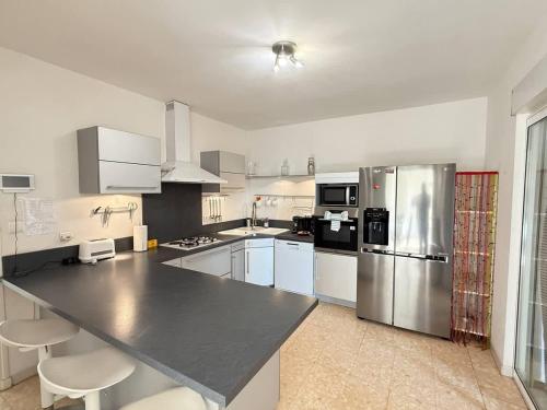 une cuisine avec des appareils en acier inoxydable et des armoires blanches dans l'établissement Villa & Appartement avec Piscine Interieure, à Valras-Plage