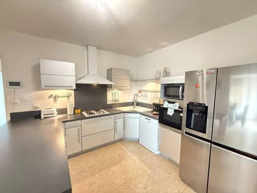 une grande cuisine avec des placards blancs et des appareils en acier inoxydable dans l'établissement Villa & Appartement avec Piscine Interieure, à Valras-Plage
