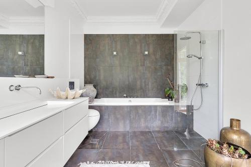 a white bathroom with a tub and a toilet at Large pool villa close to forest in Risskov