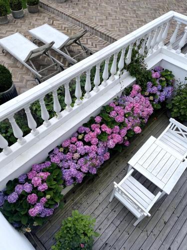 a white bench sitting on a deck with flowers at Large pool villa close to forest in Risskov