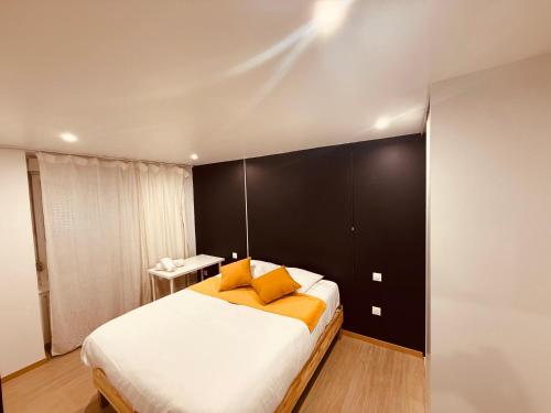 une chambre avec un grand lit avec des oreillers orange dans l'établissement La Suite Mulhouse, à Mulhouse