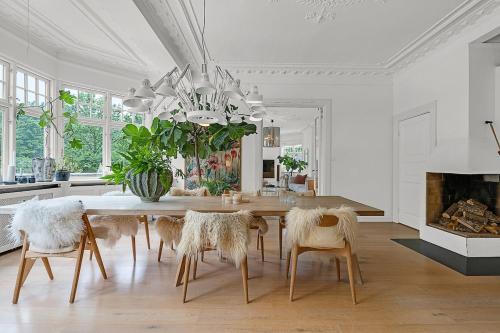 a dining room with a table and chairs and a fireplace at Large pool villa close to forest in Risskov