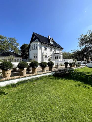 a large white house with potted plants in front of it at Large pool villa close to forest in Risskov