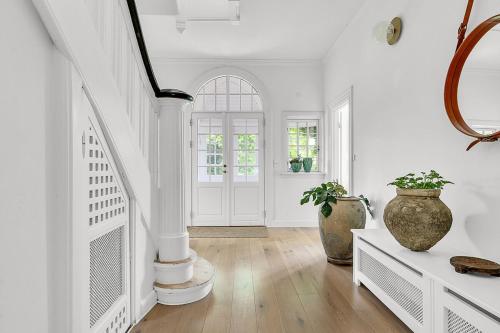 a white hallway with a staircase and vases at Large pool villa close to forest in Risskov