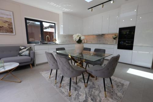 a dining room with a glass table and chairs at Luxury House for Families and Contractors, NamisSuites Serviced Apartment - Farnborough in Farnborough