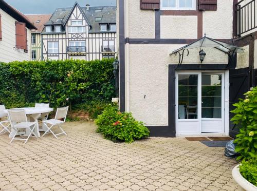 un patio avec une table et des chaises à côté d'un bâtiment dans l'établissement Deauville plein coeur, à Deauville