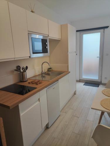 une cuisine avec des armoires blanches et un évier dans l'établissement Studio cosy entre terre et mer, à Jullouville