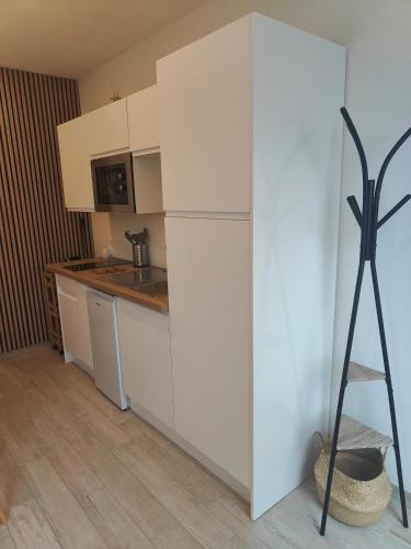  La cuisine est équipée de placards blancs et d'un réfrigérateur. dans l'établissement Studio cosy entre terre et mer, à Jullouville