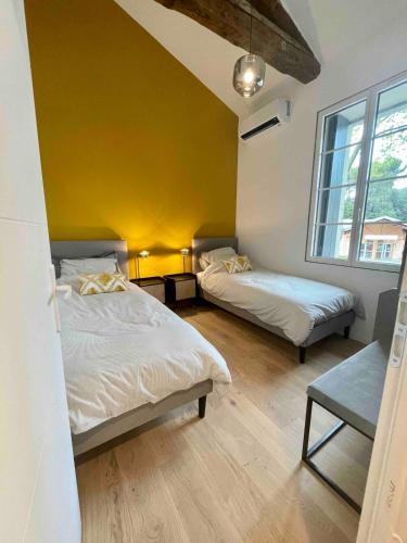 - une chambre avec 2 lits et un mur jaune dans l'établissement Appartement standing mas en pierre traditionnel, à Clapiers