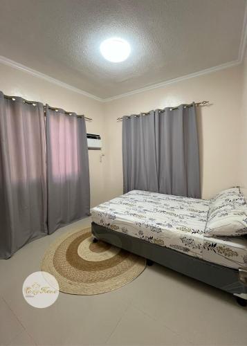 Cama en habitación con cortinas y alfombra en Cozy Home, en Dipólog