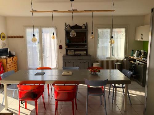 une cuisine avec une table et des chaises rouges dans une pièce dans l'établissement Maison familiale à 100 m de la plage, à Châtelaillon-Plage