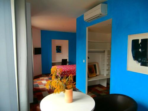 Saint-Paul-le-JeuneにあるHôtel le Moderneの青い壁の客室で、花瓶付きのテーブルが備わります。