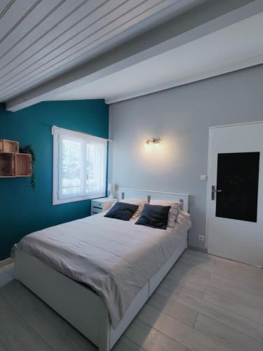 une chambre avec un grand lit aux murs bleus dans l'établissement La Villa du Moulignon, à Saint-Vincent-de-Tyrosse