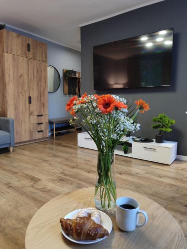 a vase of flowers and a table with a cup of coffee at Kosmonaudi Apartment in Narva