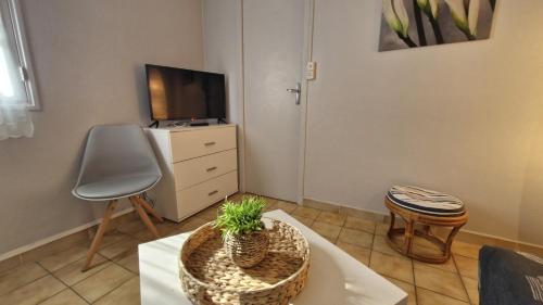 - un salon avec une table, une télévision et une chaise dans l'établissement St Georges de Didonne - AGREABLE PETITE MAISON avec COUR - 1 Chambre, à Saint-Georges-de-Didonne