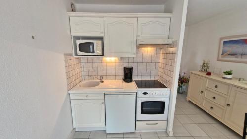 une cuisine blanche avec un évier et un micro-ondes dans l'établissement Saint Georges de Didonne - CONFORTABLE APPARTEMENT - La Dune Plein Sud, à Saint-Georges-de-Didonne