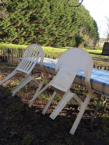 2 chaises blanches assises à côté d'un banc dans l'établissement Caravane en pleine nature, à Donnezac