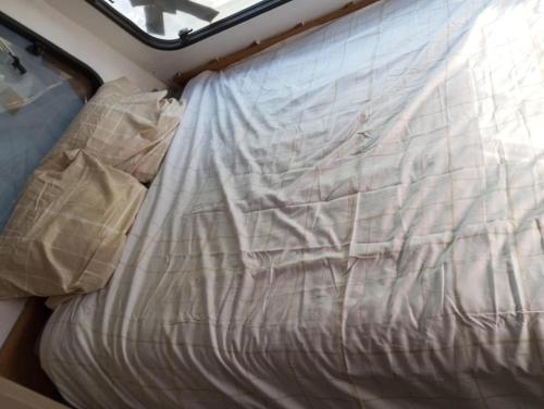 a bed with a sheet on top of it at Caravane en pleine nature in Donnezac