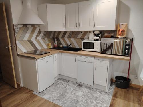 a small kitchen with white cabinets and a microwave at Appart 4/6 pers pied des pistes La Mongie in Bagnères-de-Bigorre