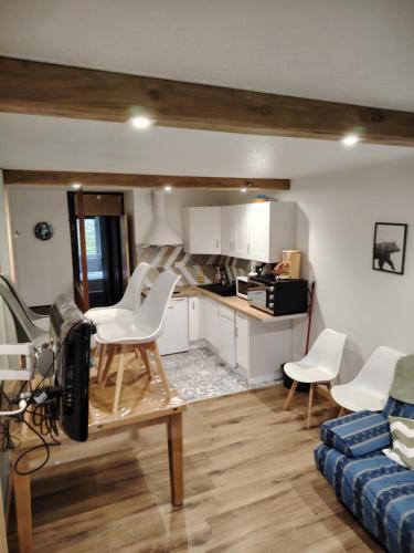 Il comprend un salon avec des chaises blanches et une cuisine. dans l'établissement Appart 4/6 pers pied des pistes La Mongie, à Bagnères-de-Bigorre