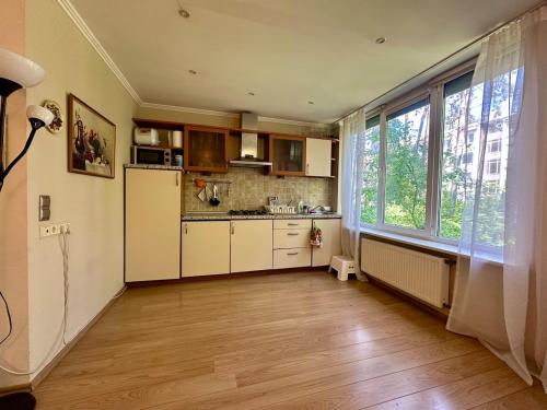 a kitchen with white cabinets and a large window at Amber Light Apartment in Jūrmala