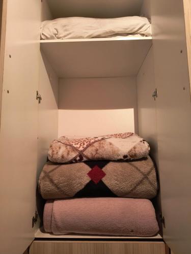 a closet with three folded towels and a bed at Flores da vovó in Campos do Jordão