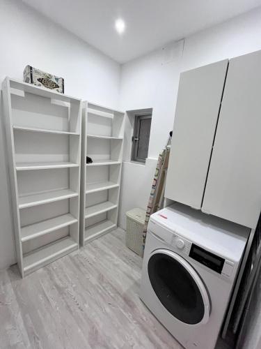 a laundry room with a washing machine and shelves at Dar Il-Ħnejja - Character Home close to Valletta in Il-Furjana