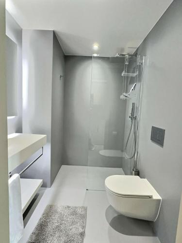 a white bathroom with a toilet and a shower at Attica Résidences, Lausanne in Saint-Sulpice