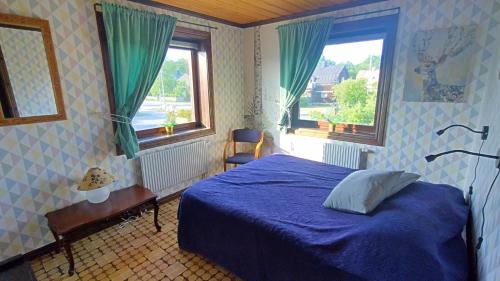 a bedroom with a blue bed and two windows at Ruth's bed and own breakfast in Skutskär