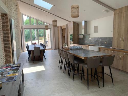 une grande cuisine avec une grande table et des chaises en bois dans l'établissement Le Moulin des Etrebières, à Cheffois