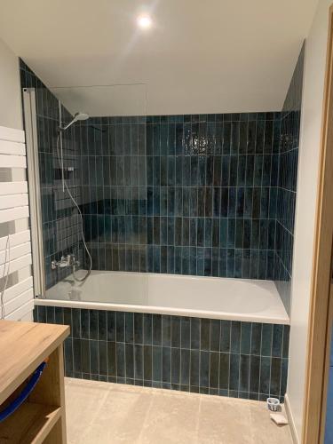 La salle de bains est pourvue d'une baignoire et d'un mur carrelé vert. dans l'établissement Le Moulin des Etrebières, à Cheffois