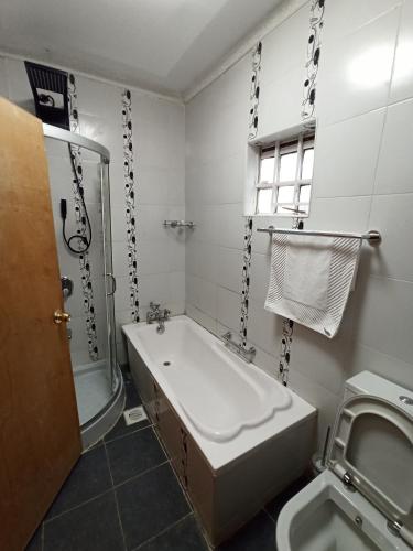 a bathroom with a tub and a toilet and a sink at Kericho Finest Home in Kericho