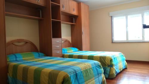 1 dormitorio con 2 camas y ventana en Apartamento Peralbar, en Carnota