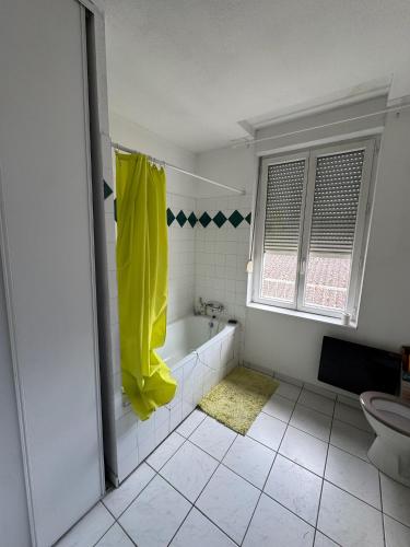 La salle de bains est pourvue d'une baignoire et d'une serviette jaune. dans l'établissement Appartement Agen, à Agen
