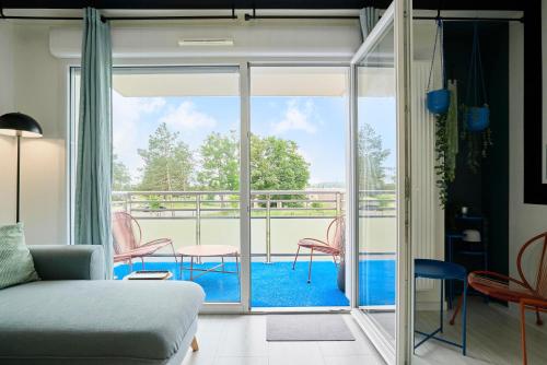 Cette chambre dispose d'un balcon avec un canapé et des chaises. dans l'établissement La Baie - Les Demeures d'Adrien, à Étaples