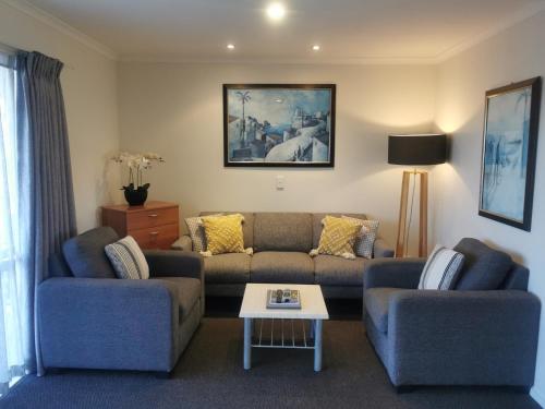 a living room with two couches and a coffee table at ASURE Ascot Motor Inn in Taupo
