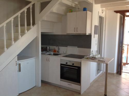 a kitchen with white cabinets and a staircase at Amalia Harbor in Halki