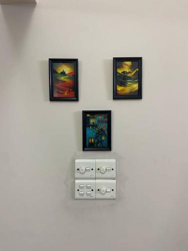 a wall with three pictures on a white wall at Home Stay Mtsbd in Dhaka