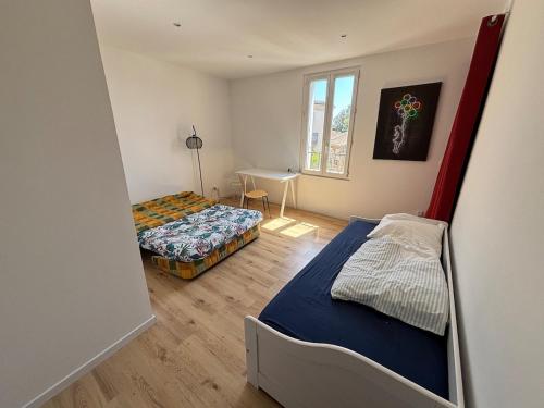 une petite chambre avec deux lits et une table dans l'établissement Appartement familial centre Saint-Georges d'Orques, à Saint-Georges-dʼOrques