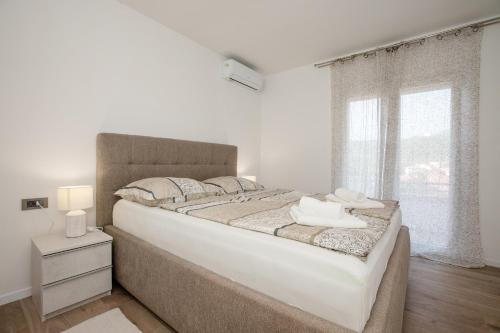 a white bedroom with a large bed and a window at Apartments Bolero in Rab