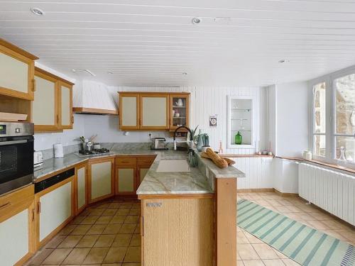 - une cuisine avec des murs blancs et des placards en bois dans l'établissement Le patio des moussaillons, à Blainville-sur-Mer