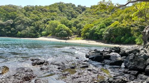 a beach with rocks and a beach with trees at Villa Prados del Rio - Guanacaste, Costa Rica in Comunidad