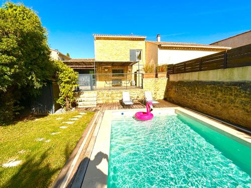 une piscine avec un jouet rose dans un jardin dans l'établissement Maison des Mûriers, 150 m2, Piscine privée, Clim, à Aigues-Vives