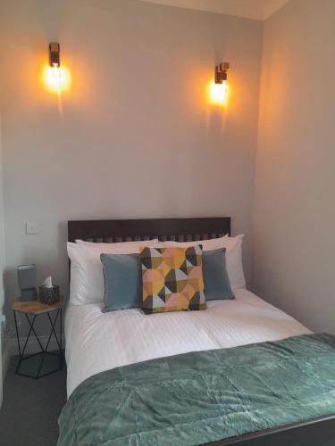 a bedroom with a bed with two lights on the wall at Outlander 4 Apartment Doune in Stirling