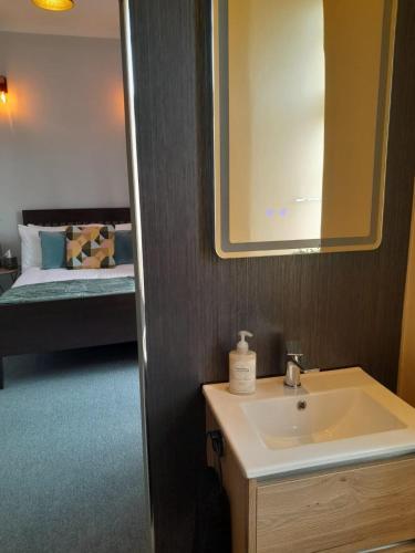 a bathroom with a sink and a mirror and a bed at Outlander 4 Apartment Doune in Stirling