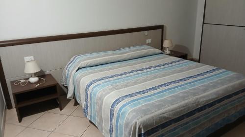 a bedroom with a bed with a striped blanket and lamps at Domo - Guest-House Il Nespolo Fiorito in Orosei