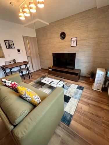 a living room with a couch and a flat screen tv at Stisfy サティスファイ in Chitose
